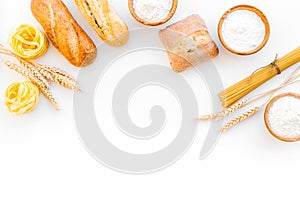 Products made of wheat flour. White flour in bowl, wheat ears, fresh bread and raw pasta on white background top view