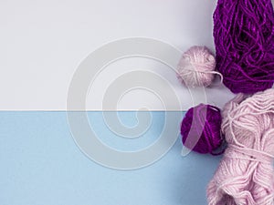 Products for needlework, knitting. Balls of pink, purple yarn on a blue background.