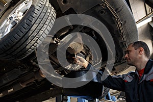 Profecional car mechanic changing motor oil in automobile engine at maintenance repair service station in a car workshop