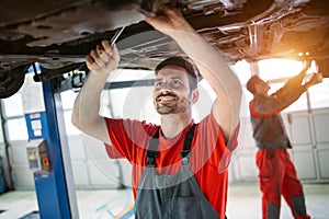 Profecional car mechanic changing motor oil at maintenance repair service station