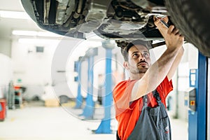 Profecional car mechanic changing motor oil at maintenance repair service station