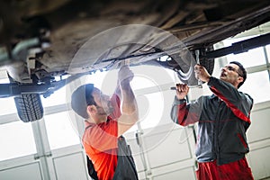 Profecional car mechanic changing motor oil at maintenance repair service station