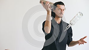 Professinal bartender man juggling bottles and shaking cocktail at mobile bar table on white background photo