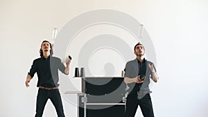 Professinal bartender men juggling bottles and shaking cocktail at mobile bar table on white background studio indoors photo