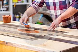 Profession, carpentry, woodwork and people concept - carpenter working with wood plank at workshop