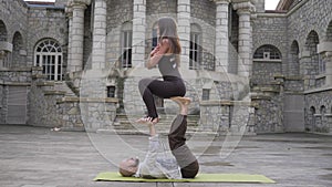 Professional acrobatic yoga. Fit caucasian couple practising plank asana pose balancing together performing acro exercises on mat