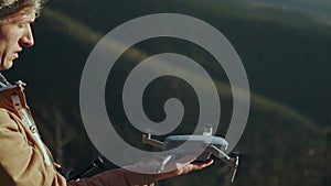 Professional aerial videomaker launches drone from hand to take video or photo. Man pilot with controller launch copter