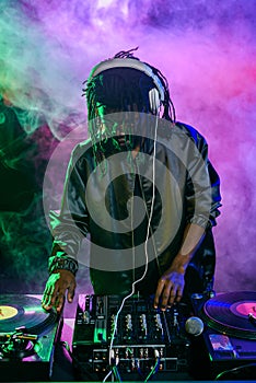 professional african american club DJ in headphones with sound mixer