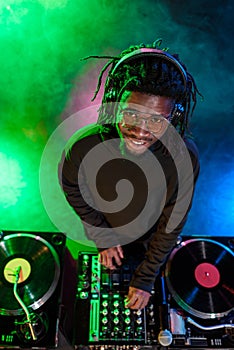 professional african american club DJ in headphones with sound mixer