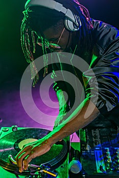 professional african american club DJ in headphones with sound mixer