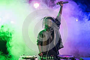 professional african american club DJ in headphones with sound mixer and microphone