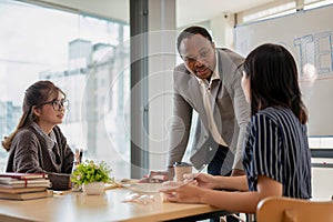 A professional African American male teacher teaching English for Asian students in the class