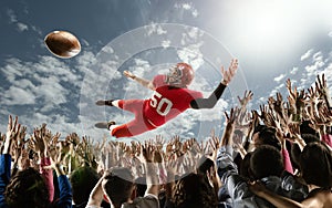 Professional american football player flies over hands of fans and catching a touchdown pass.