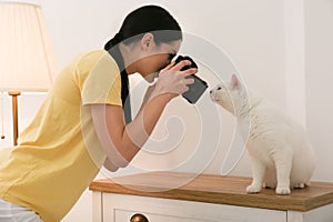 Professional animal photographer taking picture of white cat indoors