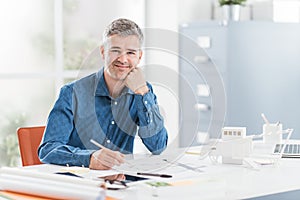 Professional architect sitting at office desk and working, he is checking a project blueprint, engineering and architecture