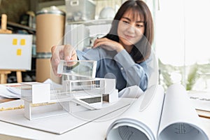 Professional architect women working in designer jobs while holding something part of modern house model on desk having blueprint