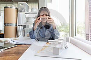 Professional architect women working in designer jobs while holding something part of modern house model on desk having blueprint