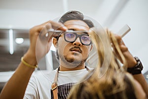 professional asian barber focused on cutting hair