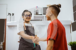 professional asian barber greeting his client doing hand shake gesture