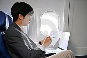Professional Asian businessman concentrating analyzing a financial data during the flight