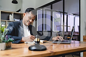 Professional Asian businessman, lawyer or financial consultant in formal suit working at his office desk, using laptop
