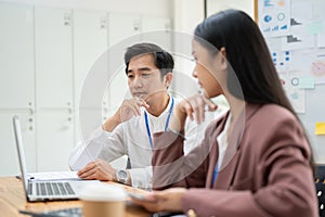 A professional Asian businessman is looking at a laptop screen with a serious thoughtful face