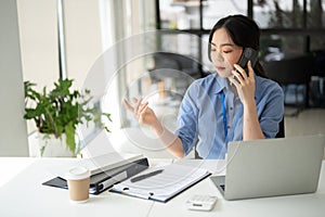 A professional Asian businesswoman is having a serious phone call with a client