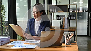 Professional Asian businesswoman is reading a document, checking her financial report