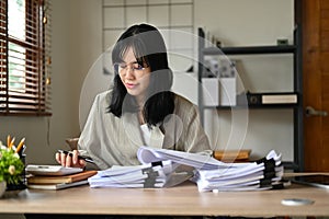 Professional Asian businesswoman working at her desk, calculating financial sales reports