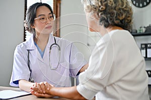 Professional Asian female doctor talking and explaining medical treatment to retire female patient