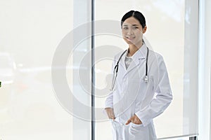 Professional Asian female doctor in uniform, standing in the hospital, hands in pocket