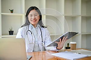 A professional Asian female doctor working and reading medical cases on her laptop at her desk