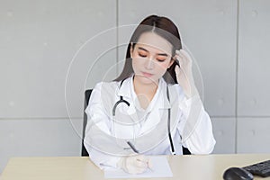 A professional Asian female doctor writes a  document in a hospital clinic examination room at the hospital health care concept