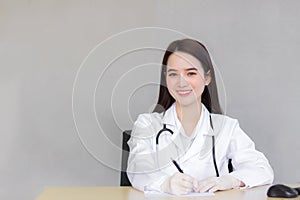 A professional Asian female doctor writes a document in a hospital clinic examination room at the hospital health care concept