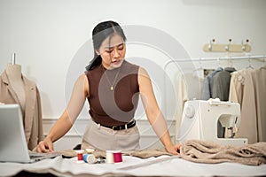 A professional Asian female fashion designer or tailor is focusing on her work in the atelier studio