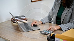 Professional Asian female lawyer working at her desk, using laptop and calculator. cropped