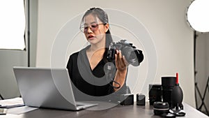 A professional Asian female photographer is focusing on checking images on her laptop