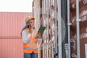 Professional asian female workerusing walkie-talkie in shipping yard industrial container box from cargo freight ship for import