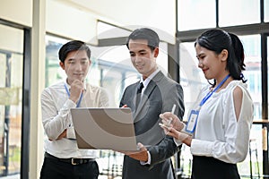 A professional Asian male boss checks his employees\' projects on a laptop