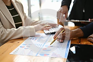 Professional Asian male financial analyst pointing his pen on financial report, analyzing data