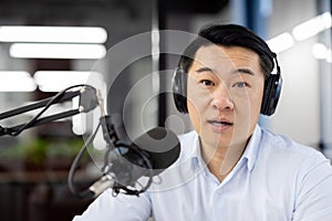 Professional asian male podcaster recording in studio with microphone