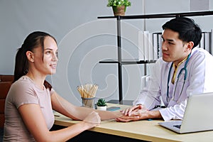 Professional Asian man Psychiatrist or neurologist is counseling and Hold hands to encourage and treament young caucasian woman.