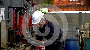 Professional asian man worker stands and maintains big machine in the warehouse factory. Concept engineer operating and control in