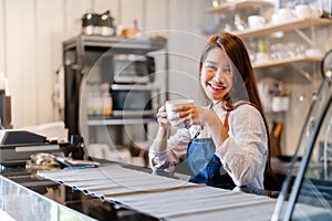 Professional Asian woman Barista preparing coffee at front counter serving coffee cup