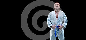 Professional athlete stands in the gym in a kimono with a blue belt. Concept of karate, jiu-jitsu, sambo, judo