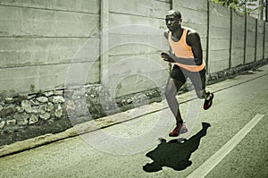 Professional athlete training - young fit and athletic black african american man doing urban running workout on asphalt road