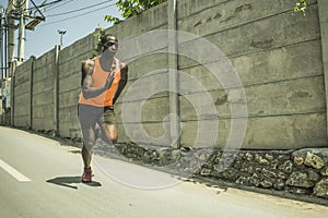 Professional athlete training - young fit and athletic black african american man doing urban running workout on asphalt road