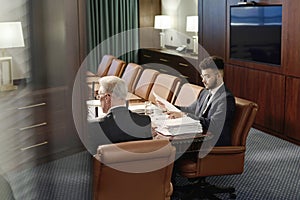 Professional Attorneys Working with Documents Sitting Side by Side at Desk