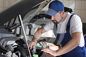 Professional auto mechanic fixing modern car in service center