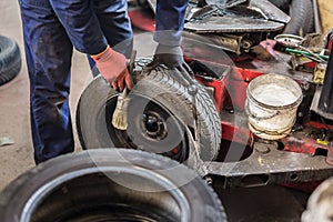 Professional auto mechanic replacing tire on wheel in car repair service.